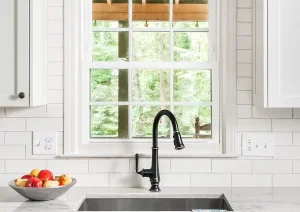 White kitchen with glass cabinet doors, butcher block counters, and black accents.