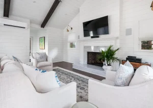 Bright modern living room with vaulted ceiling, dark beams, and white decor.
