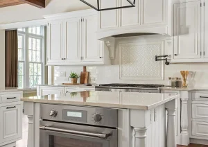 Bright white kitchen with wood beam ceiling, farmhouse range hood, and modern chandelier.