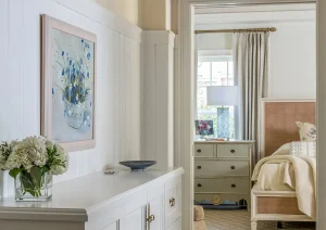 Light-filled hallway with white built-in storage, artwork, and a view into the sunroom.