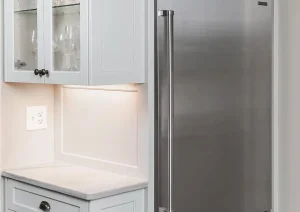 Built-in microwave and stainless steel refrigerator in a modern white kitchen.