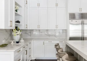 Bright white luxury kitchen with full-height cabinets, glass-front uppers, and a spacious island.