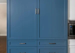 Custom tall blue pantry cabinet with drawers and brass hardware.