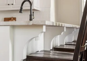 Compact coffee bar with white cabinetry, brass faucet, and espresso machine tucked beside seating area.