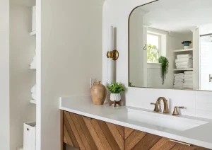 Bright modern bathroom with floating wooden vanity, oval mirror, and sleek fixtures.