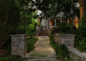 Twilight view of a stone garden entry with lush greenery and pathway lighting in New Hope, PA.