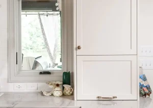 Compact beverage nook with white cabinets, oak shelves, and brass sconce in a Princeton, NJ remodel