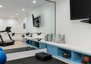 Custom-built basement media center with dual-tone cabinetry, floating shelves, and integrated wall-mounted TV in a modern Newtown, PA home.