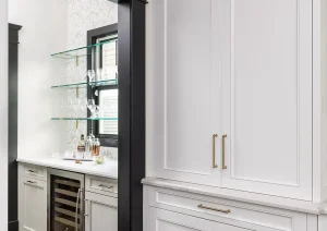 Tall white built-in pantry cabinets with integrated paneling and adjacent beverage bar.