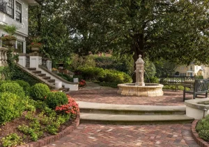 Brick garden steps with a central fountain, surrounded by manicured landscaping and mature trees.