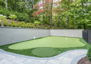 Private backyard putting green surrounded by manicured landscaping and retaining walls in Delaware Township.