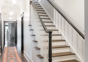 Modern staircase with black handrail, white risers, oak treads, and vintage-style hallway runner.