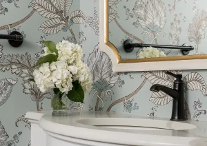 Elegant powder room with floral wallpaper, gold-framed mirror, and pedestal sink in New Hope, PA remodel.